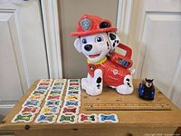 Marshall interactive toy with letter bones and Chase car displayed on wooden surface.