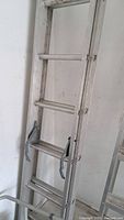 Close-up photo of upper section and locking hooks of aluminum extension ladder.