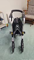 Back view of black and silver Evolution walker with folded fabric seat and dual front wheels