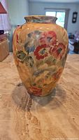 Front view of the ceramic vase displaying the hand-painted floral design with various colors including red, orange, and blue.