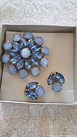 Photo of vintage floral jewelry set including brooch and matching earrings with blue glass stones and gold-tone metal.