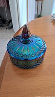 Vintage iridescent blue glass candy dish with pointed lid knob and sunburst pattern on lid.