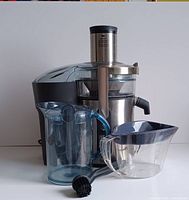 Stainless steel and black plastic Breville centrifugal juicer with juice pitcher, pulp container, and cleaning brush arranged in front.