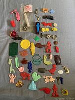 Full view of 55 assorted Cracker Jack prizes laid out showing many colorful small plastic toys and figures including whistles, characters, and animals.