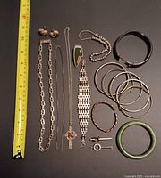 Group photo of all pieces on black surface with measuring tape showing scale