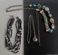 Four necklaces displayed on black and white background showing details of beads, chains, and pendants.