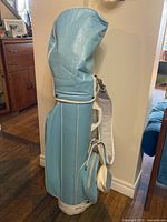 Full view of vintage baby blue golf bag standing upright with shoulder strap and pouch attached.