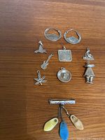 All silver charms and earrings on wood surface, showing variety of silver Mexican charms and vintage look of items.