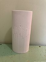 Front view of white porcelain vase showing embossed pearl water drop and line design on bisque finish exterior.