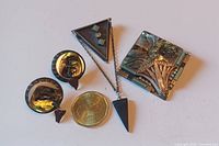 Three-piece set featuring a Langani brooch, matching earrings, and a modernist brooch with a coin for size reference.