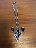 Full view of necklace and clip-on earrings laid flat on wooden surface