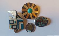 Front view of three modernist brooches with Peso coin
