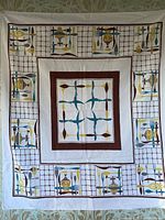 Full view of vintage tablecloth featuring kitchen cutlery print in turquoise, brown, mustard yellow on an off-white background with grid design