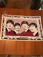 Full view of the Beatles linen tea towel showing four band members dressed in burgundy suits with musical instrument border.