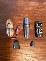 All needle cases and thimbles arranged on wooden surface showing overall lot condition and detail.