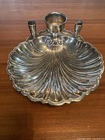 Front view of silver plated shell-shaped bowl with three built-in candleholders, showing detailed ridges and rounded edges.