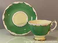 Side view of the green and gold Crown Royal Albert teacup with matching saucer showing no chips or cracks.