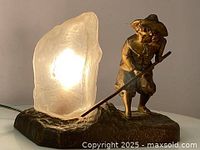 Front angle showing lamp illuminated, bronze figure, and glass shade