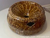 Front angle view showing brown mottled glazed pottery spittoon with diamond-shaped hole