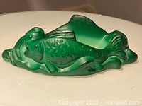 Side view of green translucent jade malachite glass bowl shaped as a fish with detailed scales and fins.