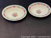 Two oval vegetable bowls with colorful floral patterns around the rim and center on a dark surface, showing top view.