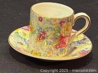 Close-up of the demitasse cup on the matching saucer showing floral chintz design and gold trim on handle and rim