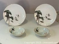 Full view of set showing two hand painted plates with pine tree and crane design, and two small matching bowls with painted scenic details.