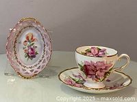Pink flower oval reticulated bowl and floral teacup with saucer, side view showing pink, white and gold colors