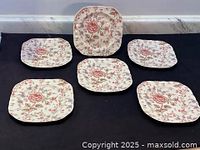 Six square salad plates featuring a floral Rose Chintz pattern by Johnson Brothers, arranged on a black surface.