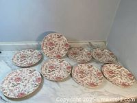 Eight Johnson Brothers Roses Chintz floral pattern dinner plates arranged on a white surface.