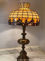 Full view of the slag glass table lamp with lit shade showing the overall design and brass base