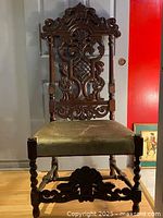 Front view of the carved walnut hall chair showing intricate carved back and green upholstered seat.