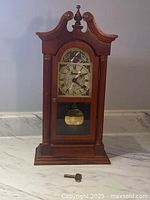 Front view of wooden mantle clock, key on surface in front