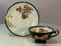 Photo of teacup and saucer set showing colorful floral designs and gold accents on black porcelain