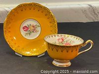 Photo of the golden-yellow Royal Albert teacup and saucer set showing the floral center on the saucer and gold filigree edging.