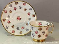 Teacup and matching saucer with hand painted floral pattern and gold rim.