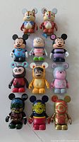 All 11 figures arranged in rows showing full front view including Chip and Dale, Buzz Lightyear, Mickey Mouse variants, and Minnie Mouse Vinylmations.