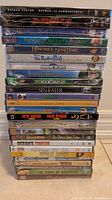 Stacked DVD movies, showing full spines, all sealed in plastic.