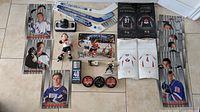 Full overview of various hockey collectibles arranged showing sticks, pucks, mini jerseys, trading cards, and figurines on floor.