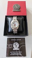 Mickey & Co. branded watch box with watch placed on black cushion inside and warranty booklet in front.