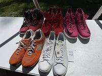 Overview of 5 pairs of men's sneakers laid out on a table showing red, purple, orange, and white styles.