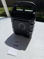 Front and side angle view showing speaker grille, handle, and top control buttons.