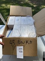 Open cardboard box showing 43 unopened teeth whitening kits packed neatly inside in 3 rows.