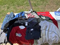 Overview of men's clothing items laid out on a table, showing shirts, jackets, and jeans in varied colors and styles.