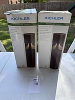 Two boxed Kichler ShowScape Series 12-Volt LED path lights standing upright on a white surface outdoors.