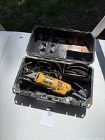 Photo of open hard plastic carrying case containing yellow DeWalt electric grinder and multiple grinding discs.