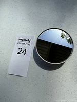 Front view of the round Google Nest Thermostat thermostat with reflective black touchscreen face showing some environment reflections.