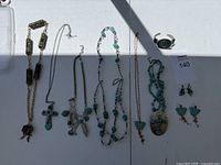 Full lot displaying various necklaces, a bracelet, and earrings laid out on white surface under sunlight with partial shadow