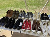 Overview photo showing all fourteen pairs of men's sneakers and casual shoes arranged on a white table outdoors.