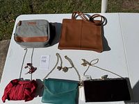 Six assorted purses and bags laid out on a table photographed in natural daylight to show all items.